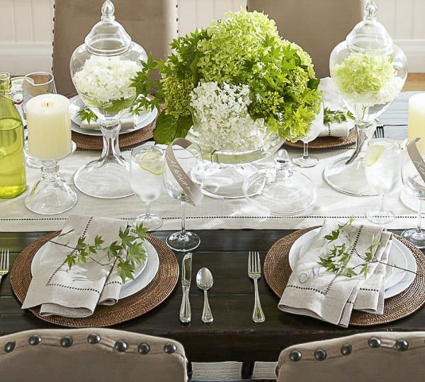 Two apothecary jars filled with floating flowers as part of a table centerpiece