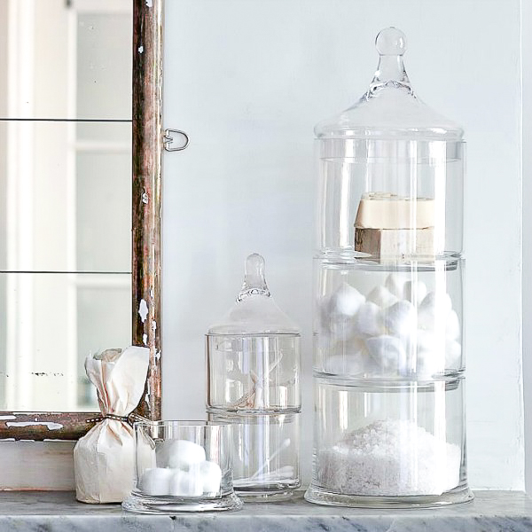Stacked apothecary jars holding cotton balls and other bathroom items