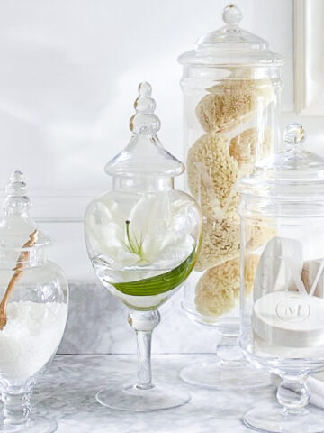 Apothecary jars in bathroom filled with bath salts, sponges, and soap