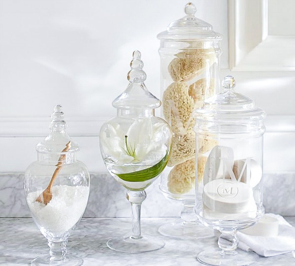 Apothecary jars in bathroom filled with bath salts, sponges, and soap