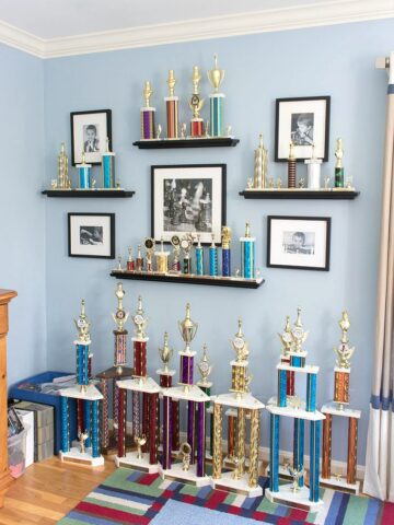 LOVE this idea for displaying kids trophies and awards on the wall - trophies sit on open shelves with black and white framed photos surrounding them