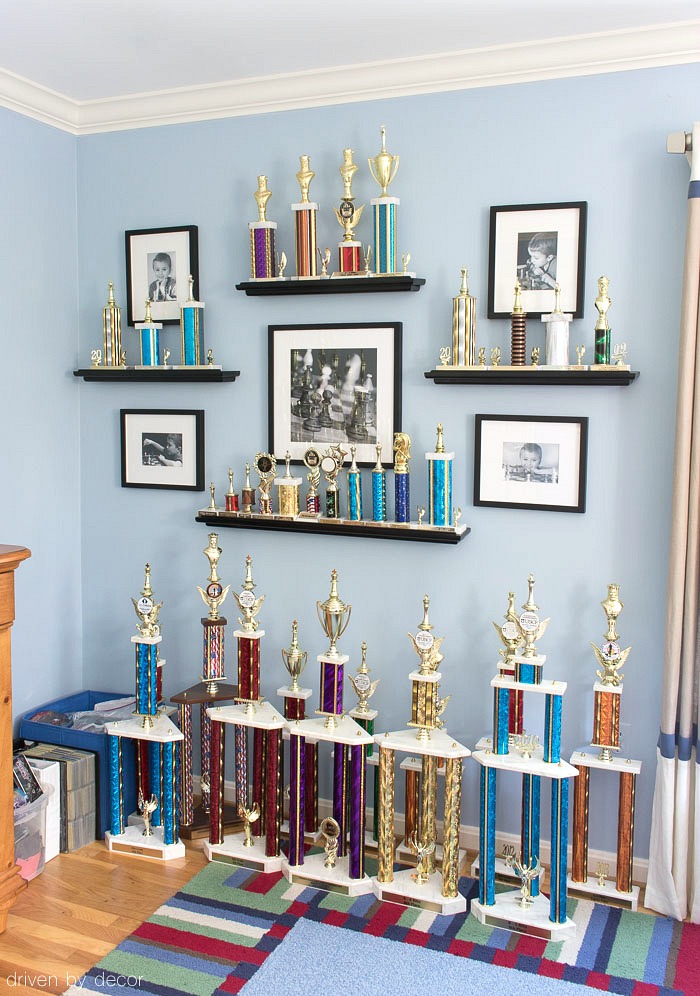 LOVE this idea for displaying kids trophies and awards on the wall - trophies sit on open shelves with black and white framed photos surrounding them