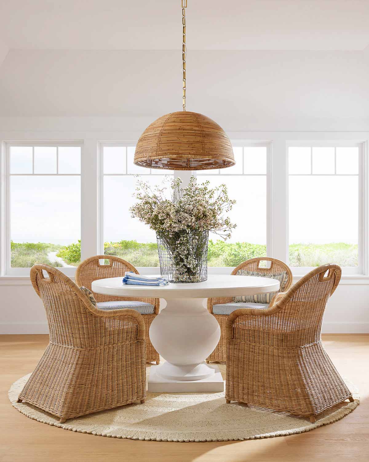 Four rattan armchairs around a round dining table