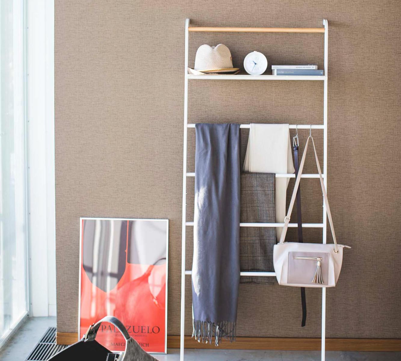 Decorative ladder with scarves, hat, & purse hung on the rungs