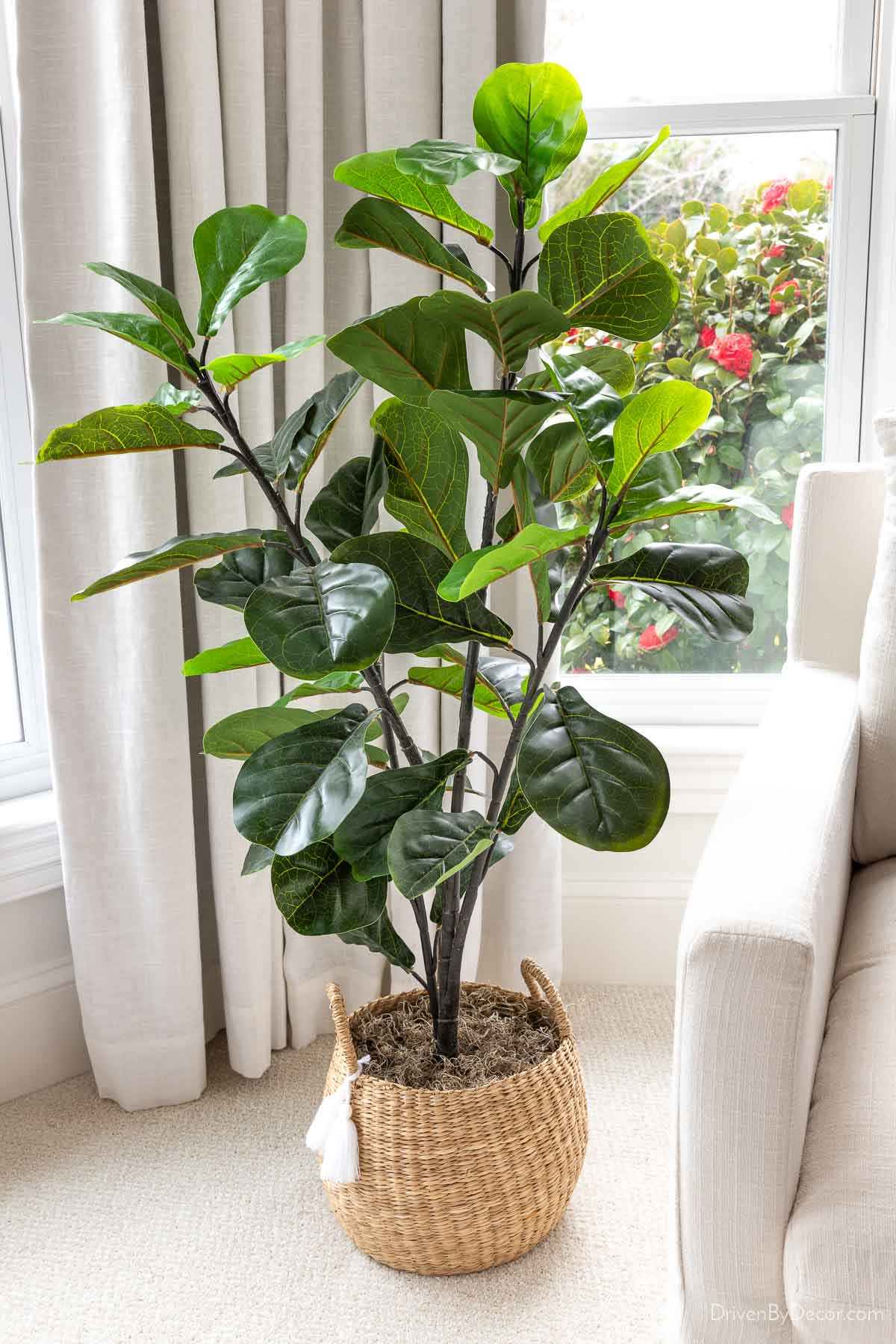 Faux fiddle leaf fig tree next to chair in bedroom