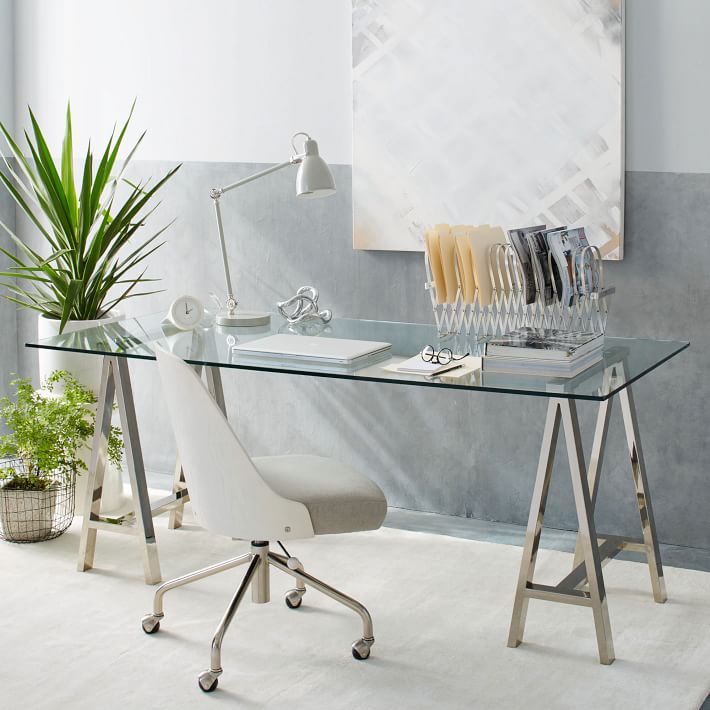 A stunning glass desk with polished nickel sawhorse legs