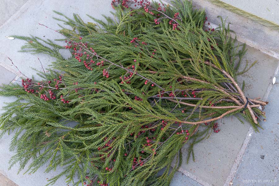 Layering greenery and berry branches to create a Christmas front door swag