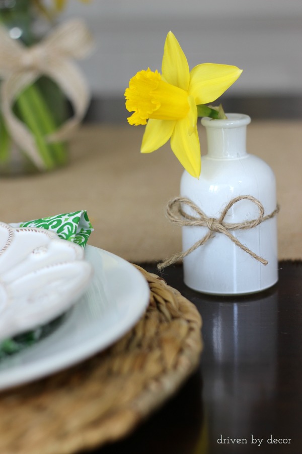 A single cut daffodil in a small vase next to each spring table placesetting