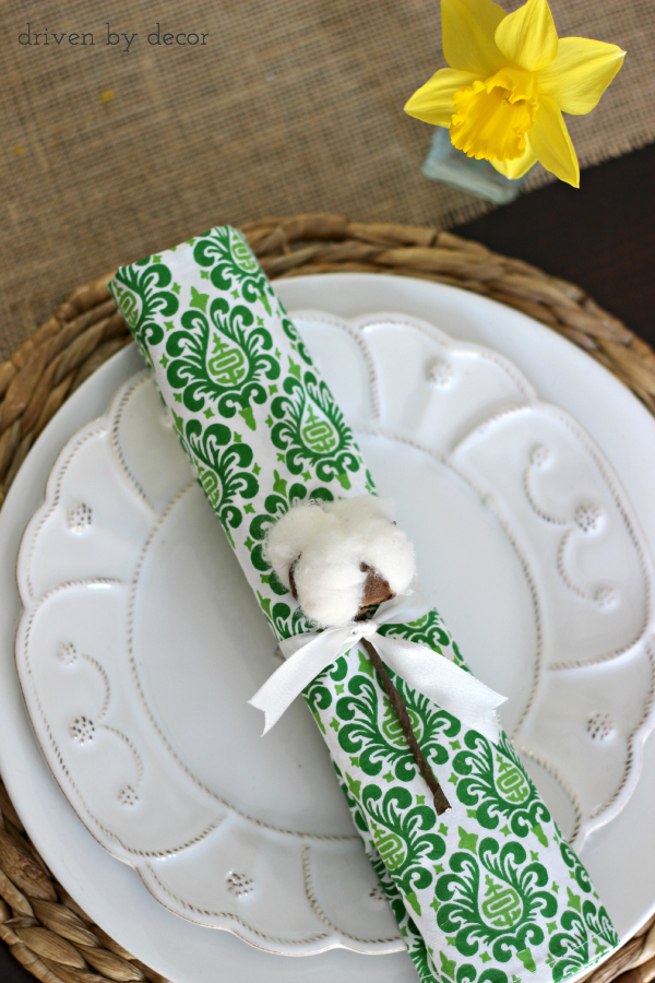 Simple spring place setting with cotton stem tied onto rolled napkin