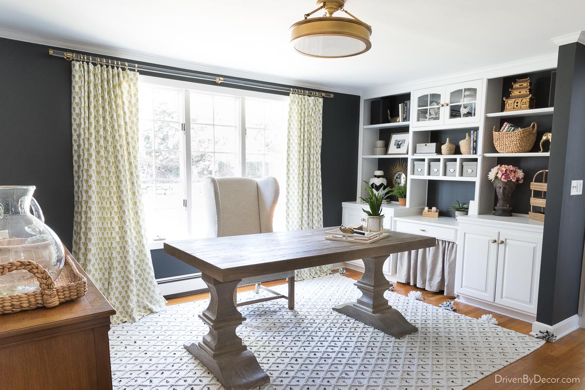 Acrylic curtain rods with patterned curtains against black walls in home office