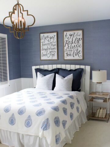 Modern coastal bedroom makeover with quatrefoil chandelier, grasscloth wallpaper, wood and chrome nightstand, and blue and white bedding - beautiful!
