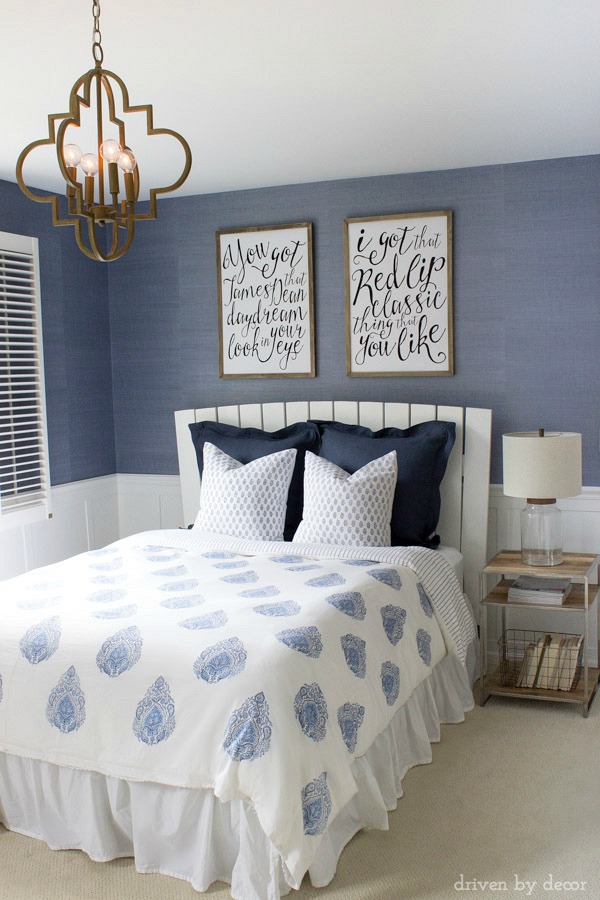 Modern coastal bedroom makeover with quatrefoil chandelier, grasscloth wallpaper, wood and chrome nightstand, and blue and white bedding. Beautiful!