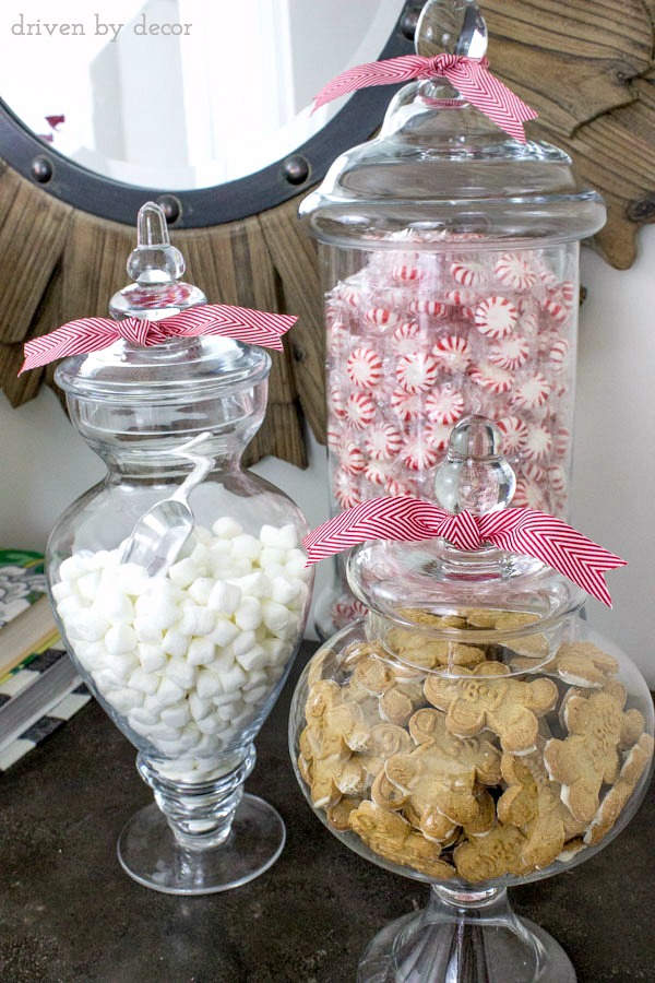 Apothecary jars filled with mints, mini marshmallows, and gingerbread men for the holidays