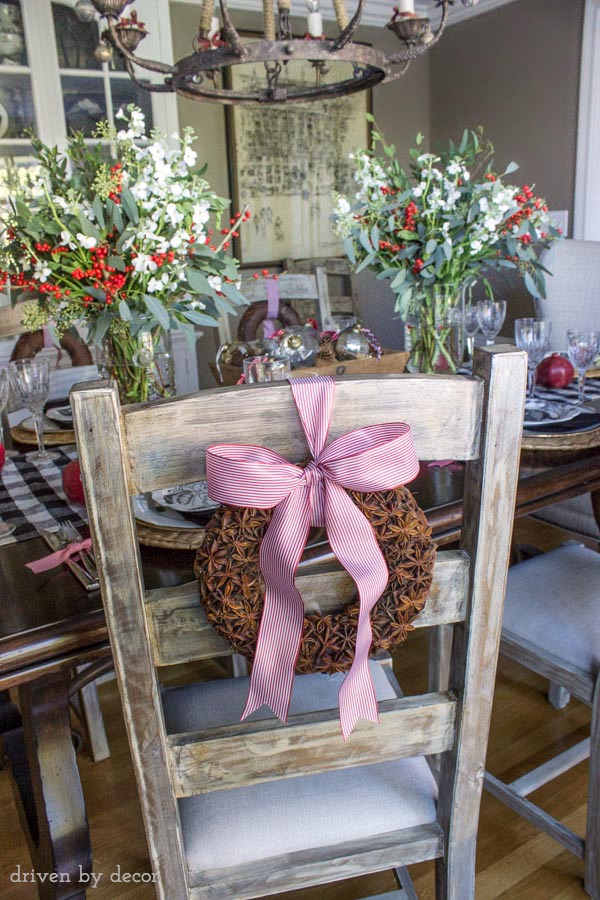 Star anise wreaths tied onto the back of dining chairs are part of this festive holiday table