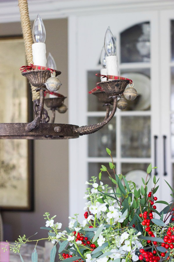 Vintage bells tied onto chandelier with ribbon add festive charm to this dining room decorated for the holidays