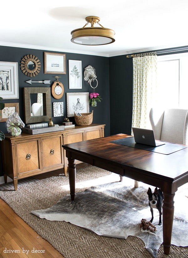 Home office with charcoal gray walls and eclectic gallery wall above a credenza