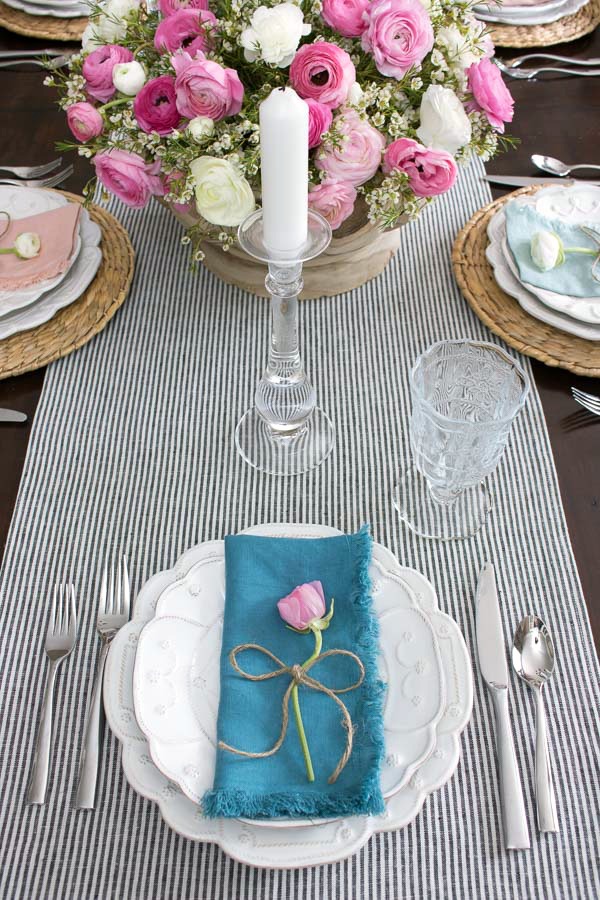 A simple placesetting for a spring tablescape - a single ranunculus tied with twine adorns each plate