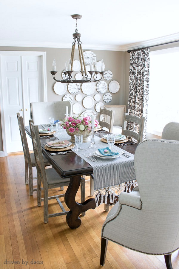 Dining room in neutrals with ladderback side chairs, upholstered wingback end chairs, rope chandelier, and a statement-making plate wall!