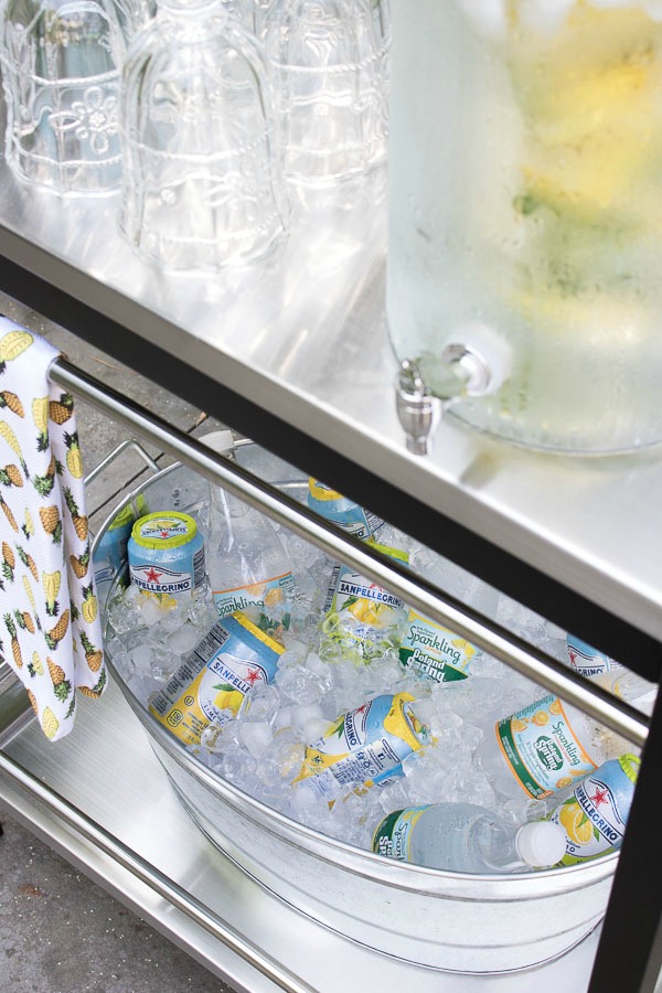 Galvanized trough with ice on the bottom of an IKEA bar cart for chilling drinks