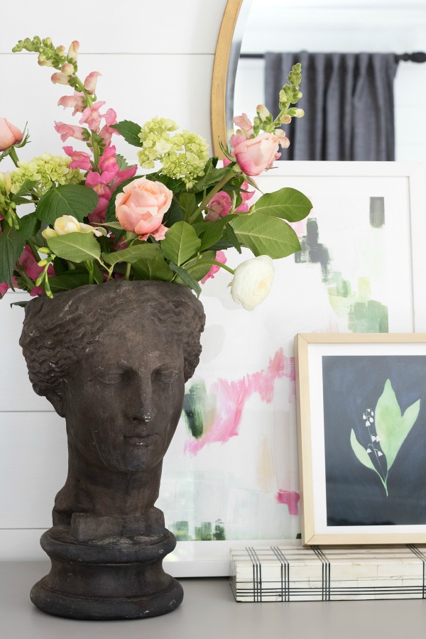 Simple dresser vignette with planter statue, decorative box, and two pieces of layered art