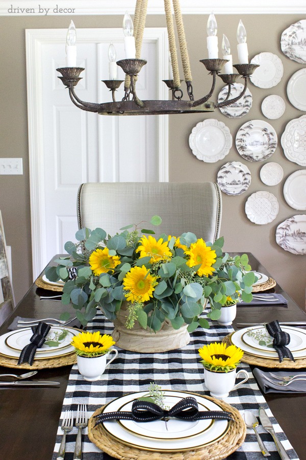 Tall tablescape with sunflowers in a wood bowl, black and white buffalo check table runner and sunflowers in teacups