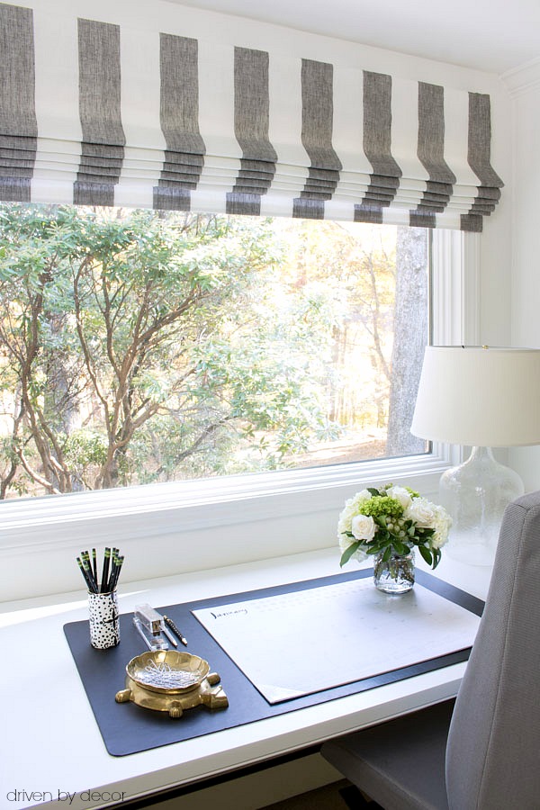 Desk area with striped Roman shades on the window