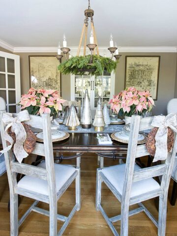 Our Christmas home tour - Christmas dining room decorated with gold and silver metallics and pink poinsettias and star anise wreaths on the chairs