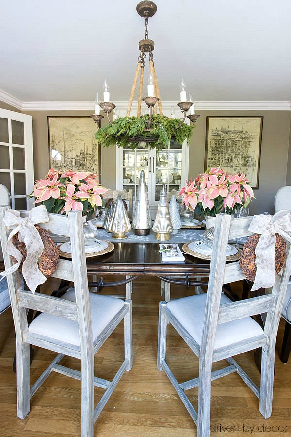 Our Christmas home tour - Christmas dining room decorated with gold and silver metallics and pink poinsettias and star anise wreaths on the chairs