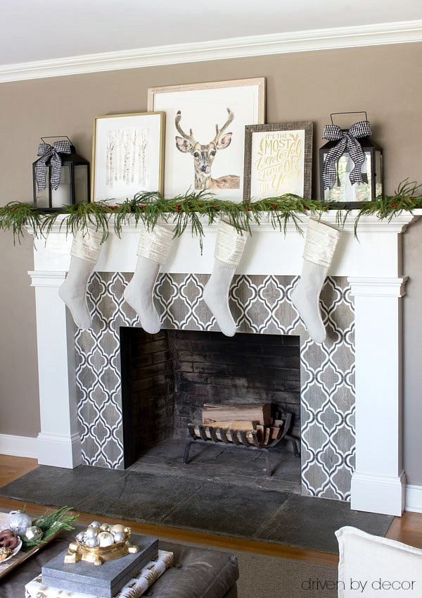 Holiday art prints, lanterns, and greenery used to decorate the mantel for Christmas