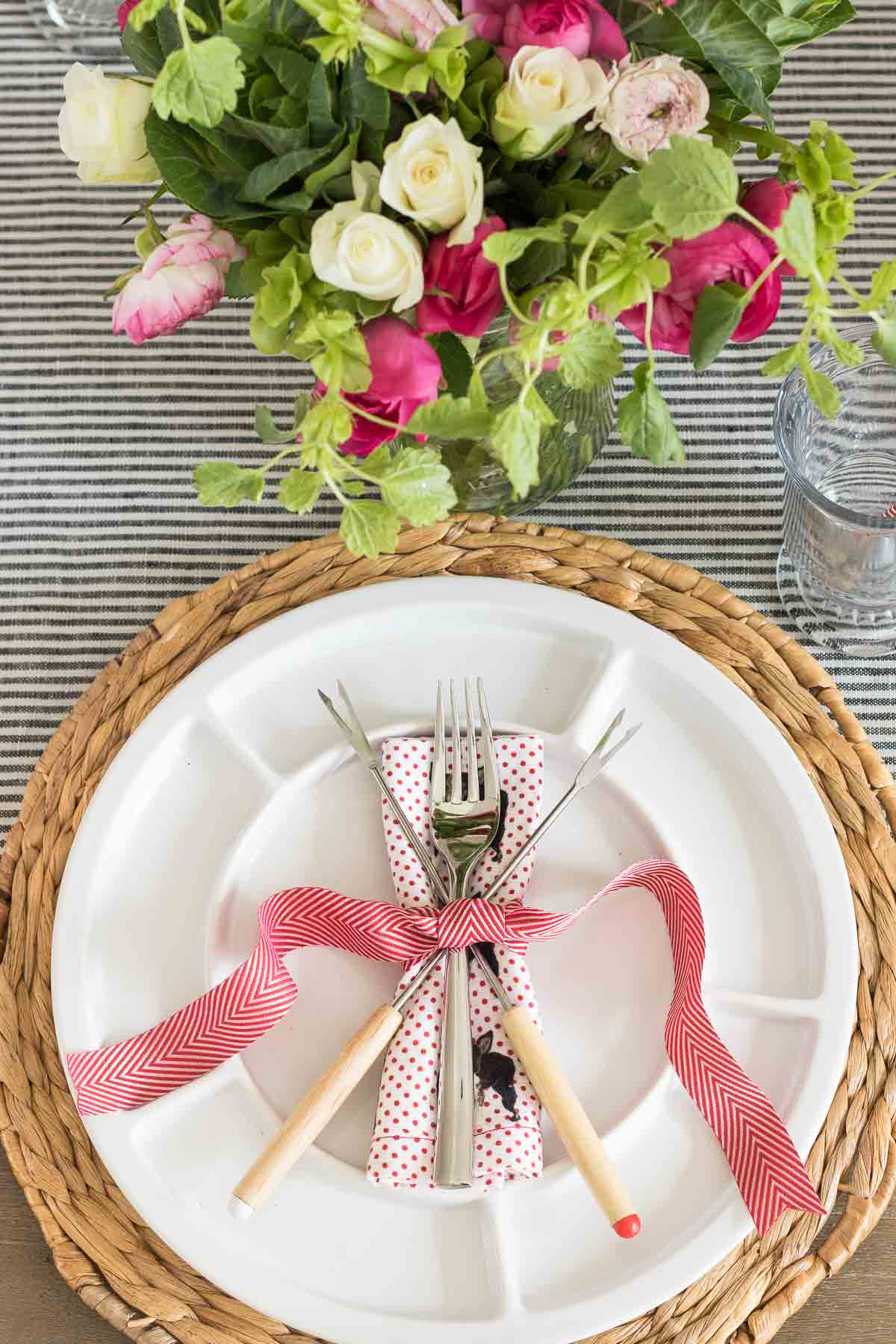 Plate, woven charger, and fondue forks arranged for fondue dinner
