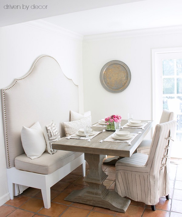 An upholstered banquette and pedestal table save space in a small eat-in area!