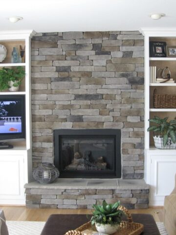 Family room with stone fireplace flanked by built-in bookcases