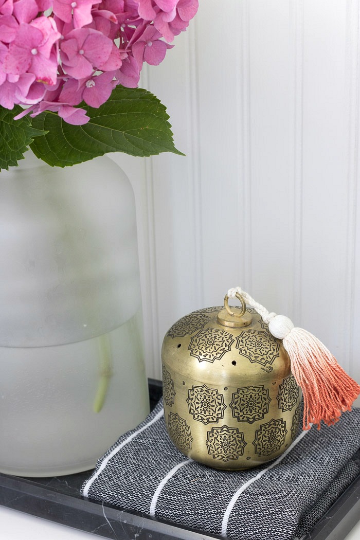 A tasseled brass vessel to hold Q-tips and cotton balls for guests - great toilet tank decor :)