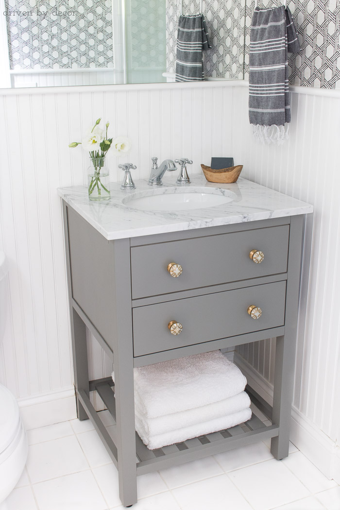 Small space single sink gray vanity with white marble top and classic Delta Cassidy bathroom faucet - links to everything in post!