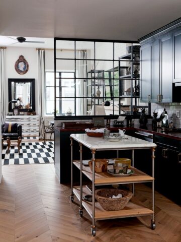 Gorgeous kitchen with freestanding marble island, herringbone wood floors, and dark cabinetry