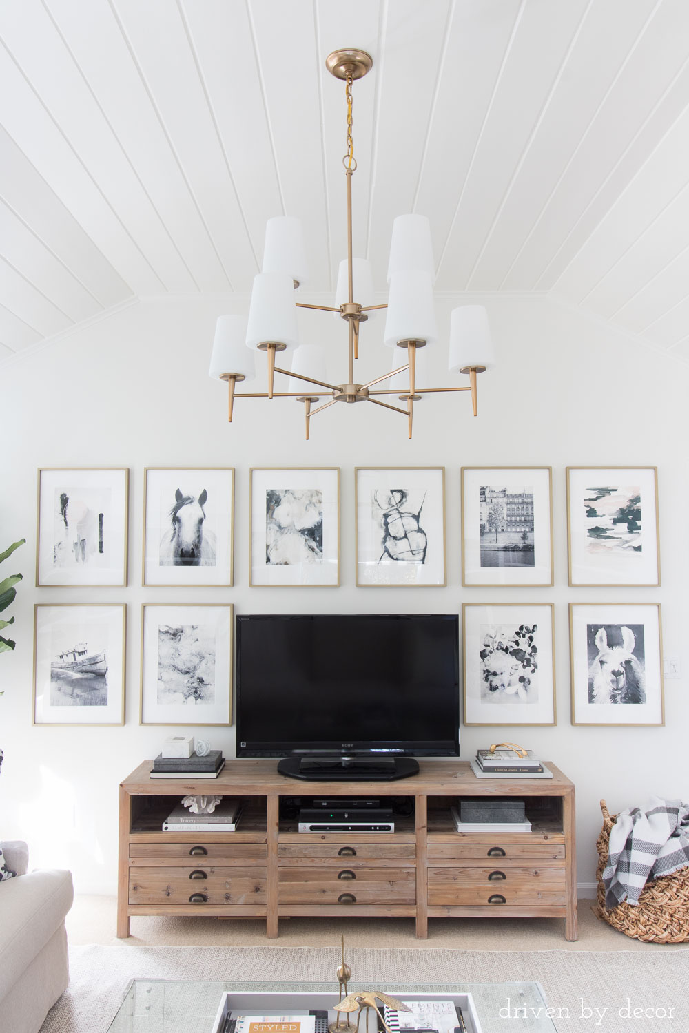 Love the art hung around the TV and that statement chandelier and wood media console!