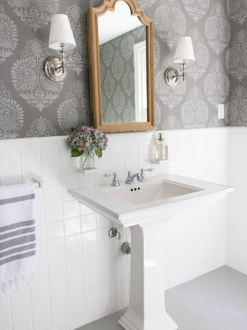 LOVE this bathroom makeover with stenciled walls that look like wallpaper, wood medicine cabinet, twin sconces, and painted tile floors!