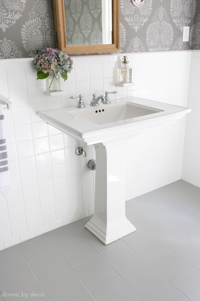 Powder room with pedestal sink on painted tile floors