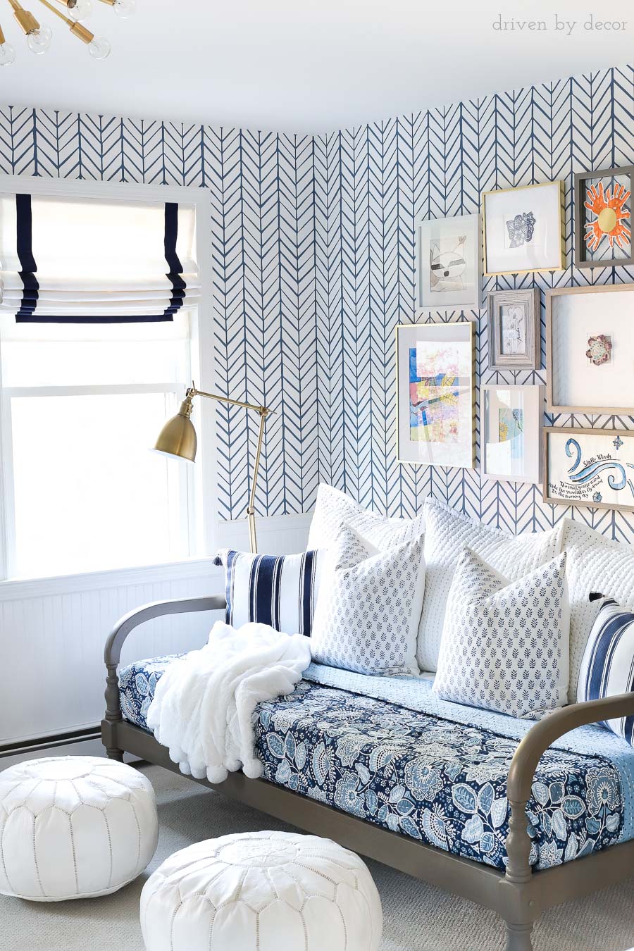 Blue and white bonus room area with daybed, blue floral quilt, blue and white pillows, white leather Moroccan poufs, Roman shades, and an art gallery wall!