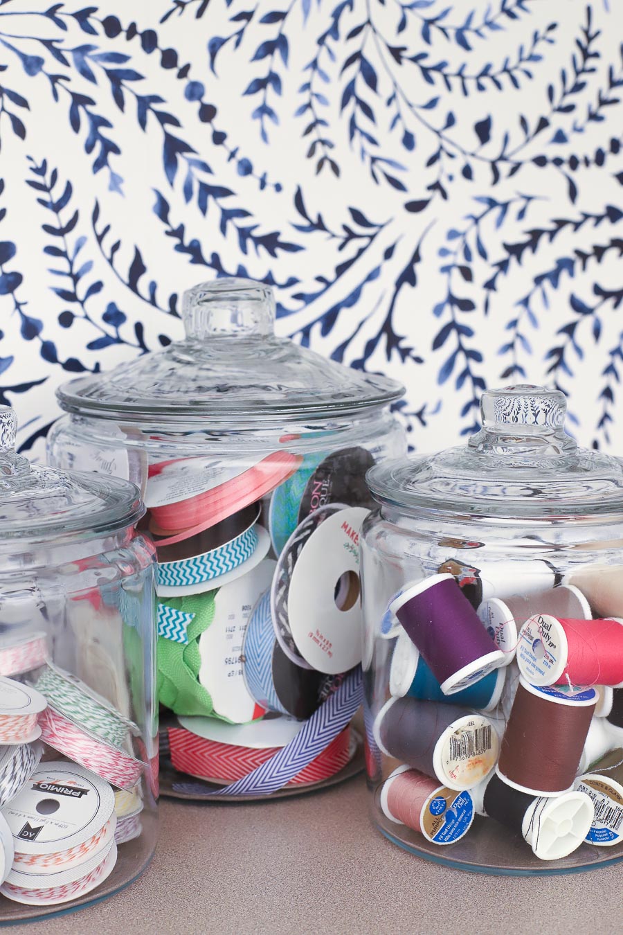 Glass storage jars hold ribbons and thread in this cute craft room!