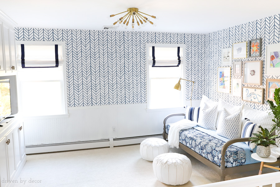 Bonus room / loft area for teens decorated with blue and white herringbone wallpaper, Roman shades, brass lighting, a daybed, gallery wall, and more! Click over for all of the details!