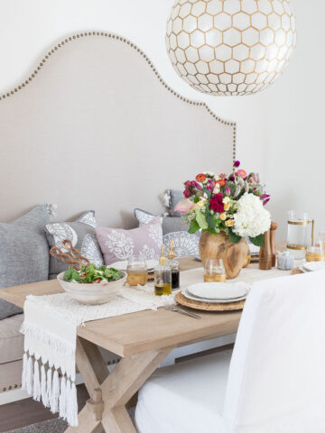 Our kitchen eat-in area with a built in banquette, trestle table, and capiz pendant lighting