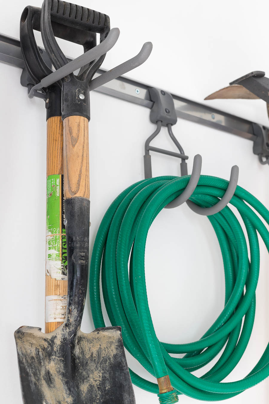 Super smart tool hooks that are part of the Elfa garage organizing system organize hoses, shovels, and all sorts of other tools!