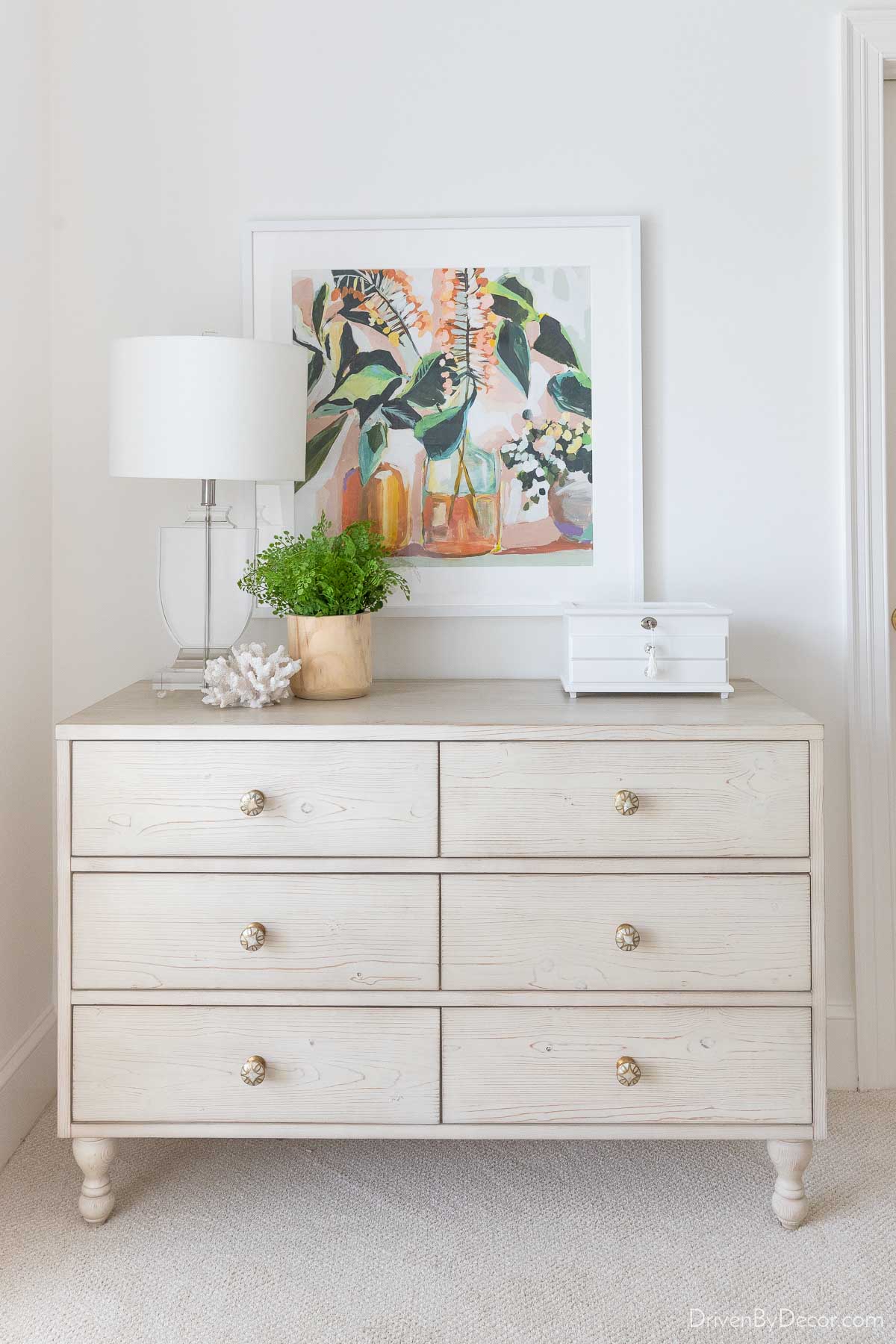 Floral picture hung over dresser to show how high you should hang art over furniture