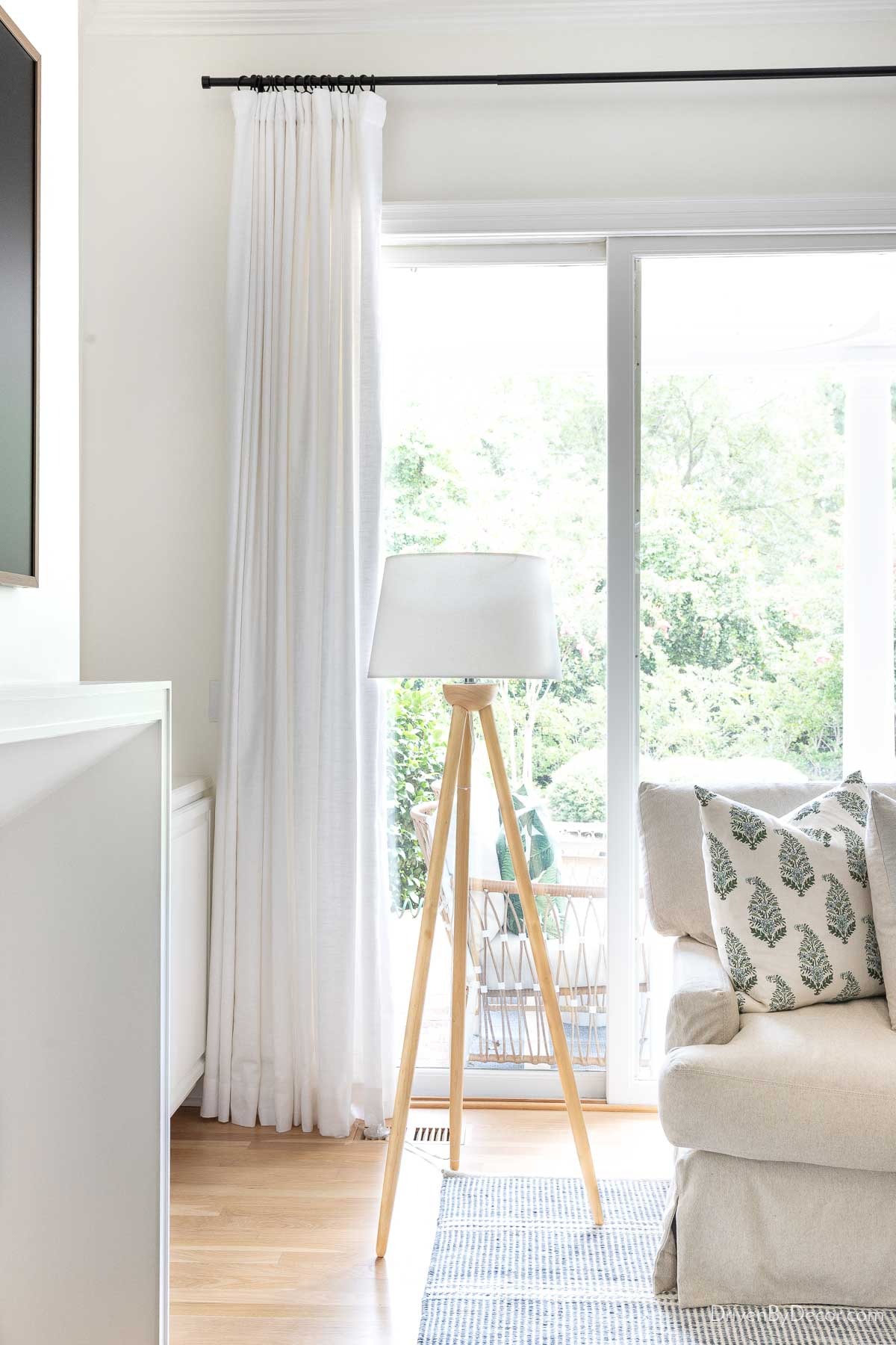 Wood tripod lamp next to sectional in family room