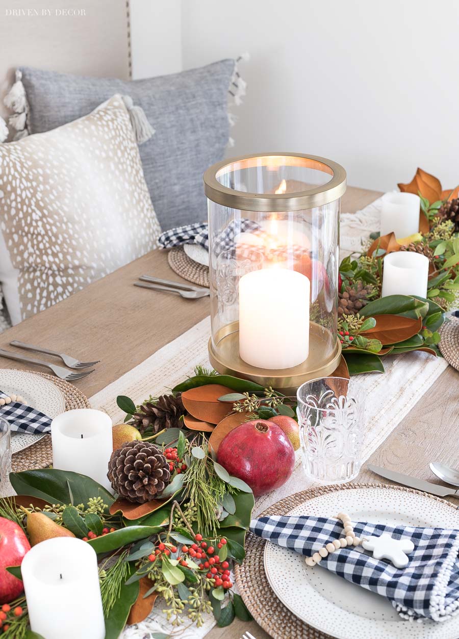 Gorgeous, festive Christmas table runner made with greenery, fruit, and pinecones. Post includes a step by step tutorial to make it!