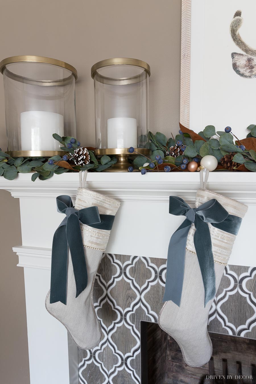 Our fireplace mantel at Christmas with brass hurricanes and a eucalyptus garland