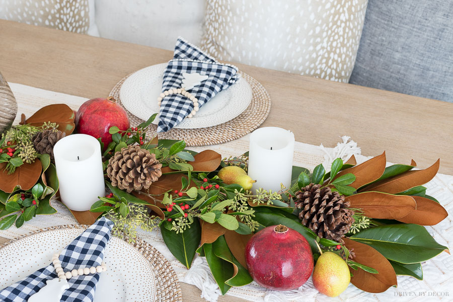 Fresh greenery table runner made with magnolia leaves, eucalyptus, berries, pinecones, pomegranates, and pears