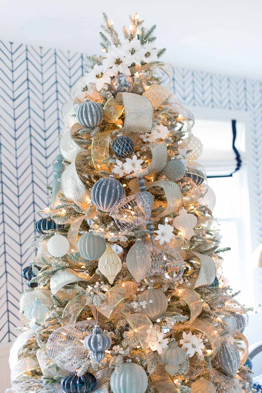 Faux white poinsettias spiral up the top of this gorgeous tree instead of a tree topper!