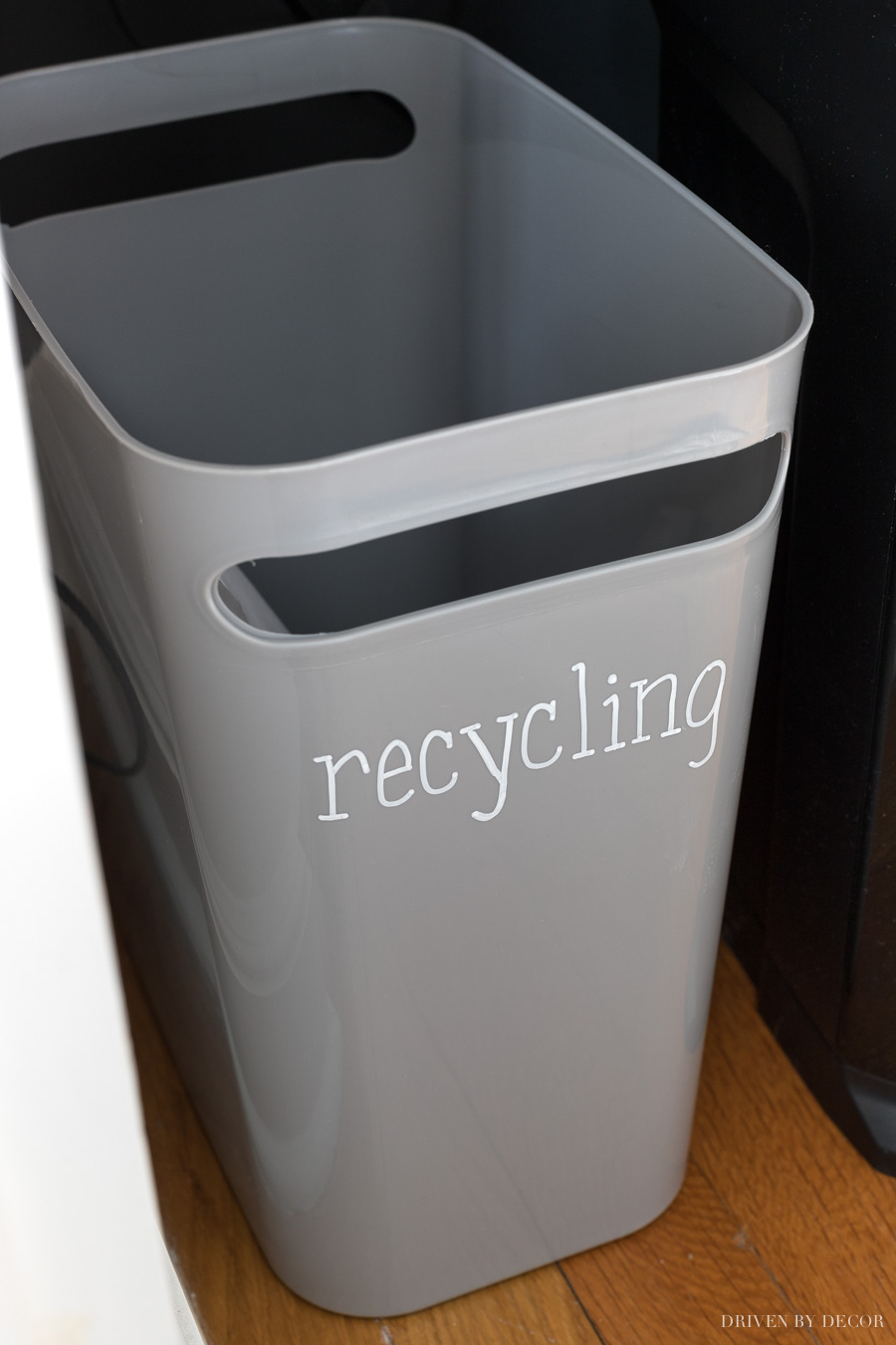 Slim gray trash can labeled for recycling with a chalk pen